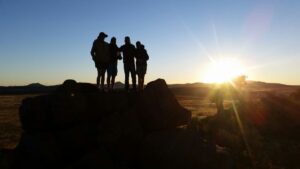 group of people standing on Karoo rock in sunset